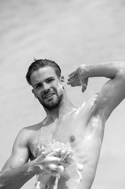 Sağlık ve cinsiyet kavramı. Açık gökyüzü arka plan üzerinde gülümseyen kıl olan adam. Maço köpük sünger ile çıplak göğüs Yıkama