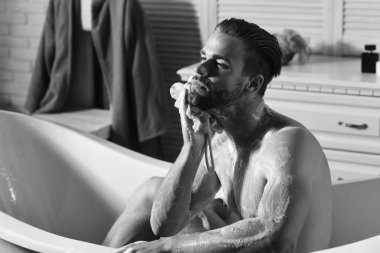 Sakal ve rüya gibi yüz köpükle kaplı olan adam. Cinsellik ve gevşeme kavramı: maço kaplı küvet içinde köpük ile