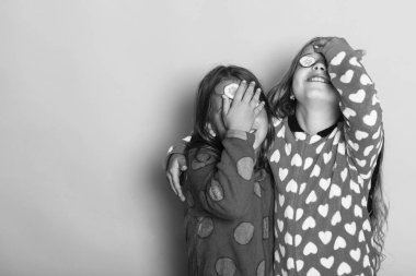 Çocuklar, pembe arka plan poz, alanı Kopyala. Kızlar renkli polka noktalı pijama sarılmak ve gözlerimizi kapamamızı söylediler