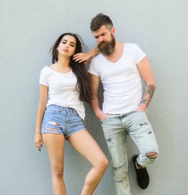 Kentsel sevgi dolu çift. Çift beyaz gömlek birbirlerine dikkat ediniz. Hipster sakallı ve şık bir kız açık havada takılmak. Aşık çift birlikte gri duvar arka plan asmak. Çift şık modern gençler