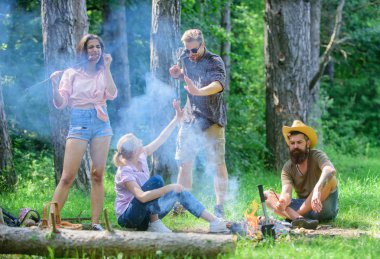 Büyük piknik için toplama. Şirket sosis sopa üzerinde kavurma eğleniyor. Şenlik ateşi takılmak ve hazırlamak için toplantı arkadaşlar sosis aperatifler doğa arka plan kavrulmuş. Yaz piknik katılmak