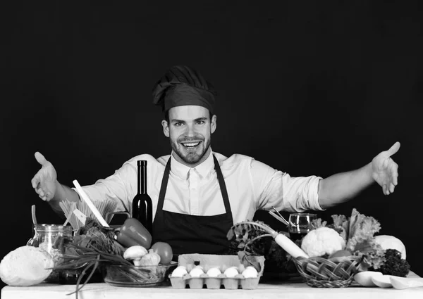 Kock med glada ansikte på svart bakgrund. Köksutrustning och matlagning koncept. Cook sitter i köket — Stockfoto