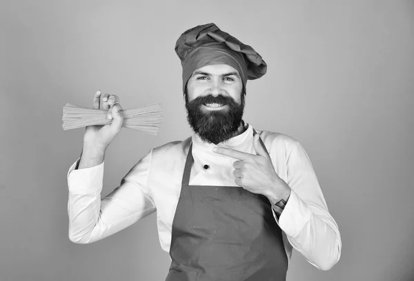 Szakács spagetti csomó. Olasz konyha koncepciót. Ember vagy csípő szakáll rendelkezik makaróni, piros háttér. — Stock Fotó