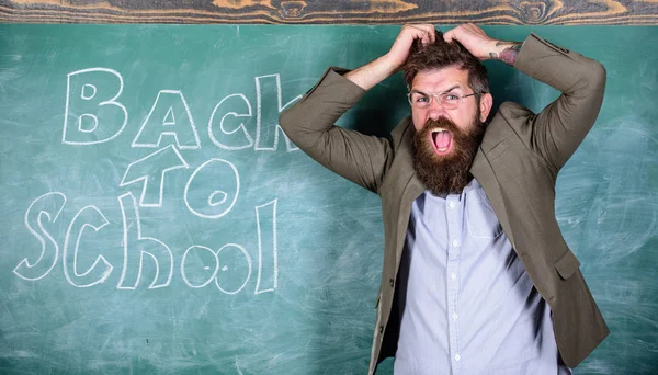 学校が嫌い。教師や教育者は学校に戻って碑文と黒板のそばに立ちます。先生は、不幸な顔で叫んでヒステリック。スクーリングについては、先生が狂った。男は拒否は学校で作業を開始します。 — ストック写真