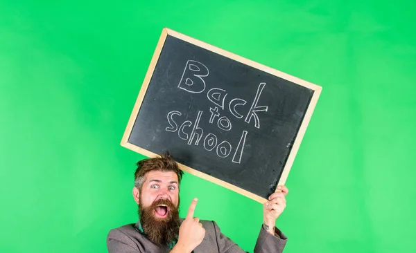 Solicite una oferta educativa sensacional. Volver a la escuela oferta especial. Oferta especial descuento venta temporada escolar. Hombre barbudo profesor sostiene pizarra de nuevo a la inscripción de la escuela sobre fondo verde —  Fotos de Stock