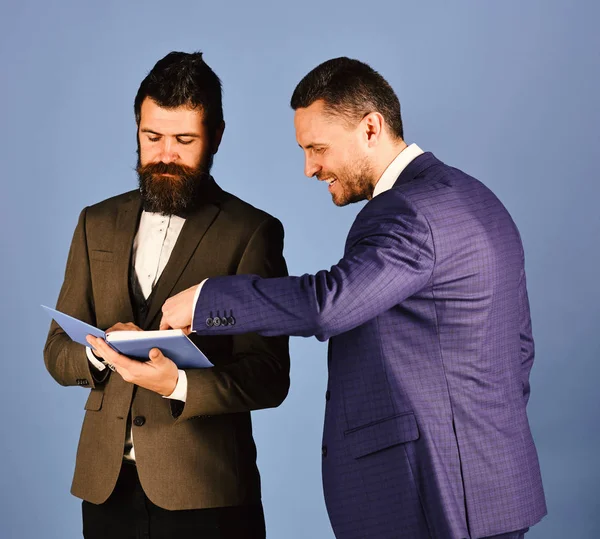 Machos em ternos clássicos falar sobre cronograma. Homens com rostos sorridentes ler livro azul . — Fotografia de Stock