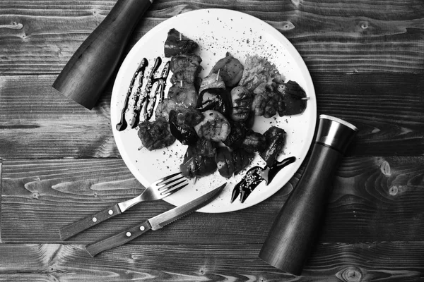 Porc rôti et légumes grillés sur fond bois. Concept de cuisine traditionnelle. Fourchette, couteau, sel et poivre — Photo