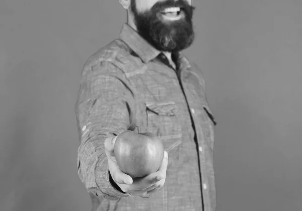 Mann mit Bart hält grüne Früchte in der Hand, isoliert auf grünem Hintergrund, aus nächster Nähe. Bauer hält lächelnd einen frischen Apfel in der Hand. Landwirtschaft und Herbstprodukte — Stockfoto
