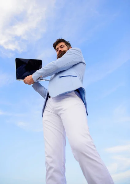 よく手入れされたひげそりのヒップスターはノートパソコンの青い空の背景を保持する。男は現代の技術マネージャー起業家に正式なスーツ。連絡を取り合って。現代の通信だ。優れた管理者の最高品質 — ストック写真