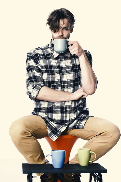 Cabello desaliñado en la cara seria sosteniendo taza azul aislado sobre fondo blanco. guapo chico sosteniendo tazas aislado en blanco fondo — Foto de Stock