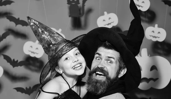 Mago e strega col cappello nero. Ragazza e barbuto uomo con facce sorprese su sfondo rosso — Foto Stock