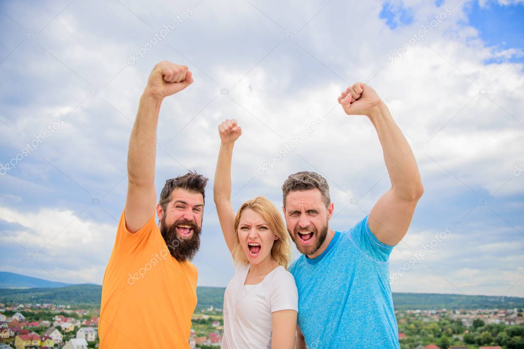 Ways to build ohesive team. Woman and men look confident successful sky background. Threesome stand happy confidently with raised fists. Behaviors of cohesive team. Celebrate success. Yes we can