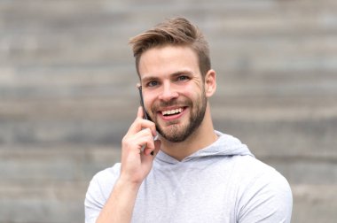 Konsept konuşalım. Cep telefonundaki mutlu adam konuşması. Genç adam dışarıda konuşmak için akıllı telefon kullanıyor. Arkadaşınla dertsiz tasasız konuş. İyi haberleri paylaşıyoruz.