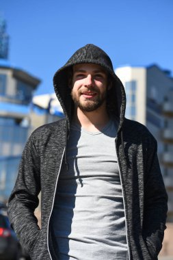 Sakal konsepti. Tıraşsız suratlı sakallı bir adam. Kapüşonlu genç adam güneşli açık havada