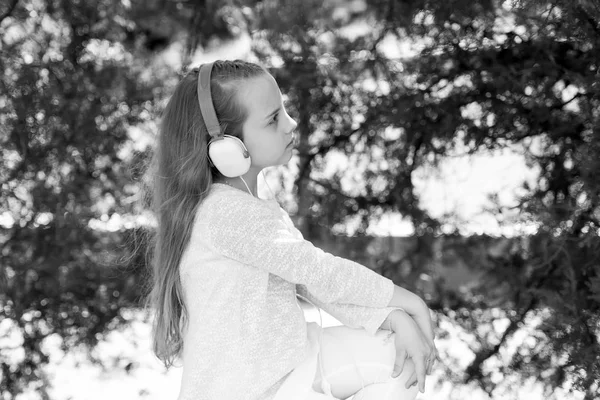 Liten flicka lyssna musik i sommar park. Barn njuta av musik i hörlurar utomhus. Mode barn och modern teknik. Melody ljud och mp3. Sommar semester vila och roliga — Stockfoto