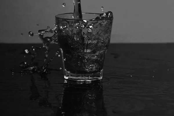 Salpicadura de agua en vaso para whisky sobre fondo rojo, vista lateral . —  Fotos de Stock