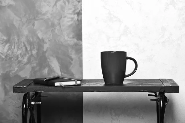 Conceito de leitura, escrita e educação. Xícara de bebida quente e caderno em pequena mesa. Xícara de chá ou café e diário sobre fundo elegante. Bebida quente e caderno em mesa baixa perto de wal . — Fotografia de Stock