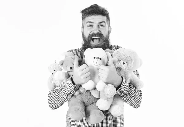 Homem com cara feliz segura pilha de brinquedos macios, polegares para cima gesto. Macho com barba abraça muitos ursos de pelúcia e brinquedos de pelúcia . — Fotografia de Stock