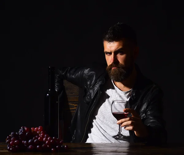 Człowiek z brodą trzyma kieliszek wina na ciemnym tle brązowy. Sommelier smakuje drogich napój. Pojęcia gdzie i degustacyjne. — Zdjęcie stockowe