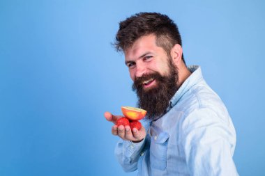 Muamele etmek var. Sakallı hippi çilek ve elma avuç içinde tutar. Elma meyve mavi arka plan davranır ve çilek denemek adam sunuyor. Sakallı adam kurnaz yüz organik davranır sunar