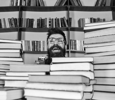 Öğretmen ya da öğrenci sakallı gözlük takmaz, defocused kitaplar ile masada oturur. Adam kazık kitap kütüphane, kitap rafı arka plan üzerinde arasında heyecanlı yüzünde. Bilimsel bir keşif kavramı