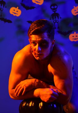 Korkunç yüzü ve kaslı gövdesi olan adam mavinin üzerinde duruyor.