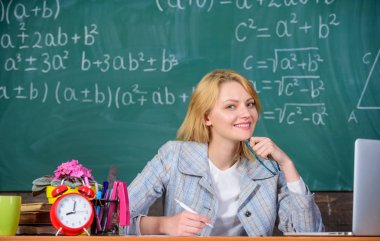 Öğretmen kadın sit tablo kara tahta arka plan. Sınıf organize etmek ve öğrenme süreci kolay ve anlamlı. Mükemmel communicability ve kişilerarası becerileri. İyi organize ve kararlı öğretmen