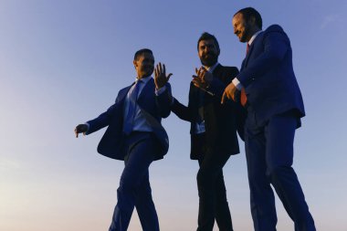 İş, başarı ve işbirliği kavramı. Şirket liderlerinin günbatımı gökyüzü arka plan üzerinde yürümek