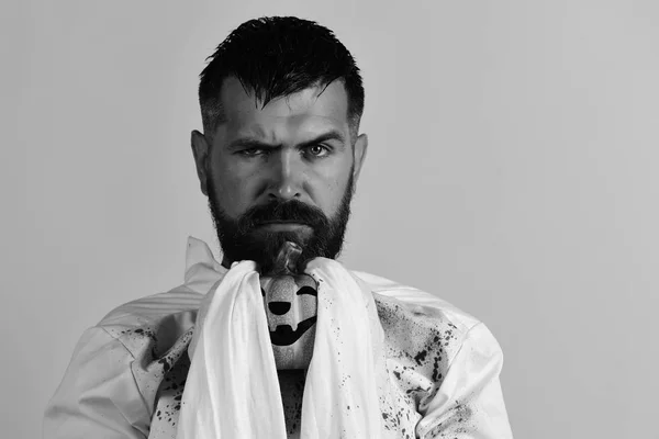 Hombre con cara seria aislado sobre fondo amarillo, espacio para copiar. El tipo con barba sostiene la calabaza naranja. Halloween y feliz fiesta — Foto de Stock