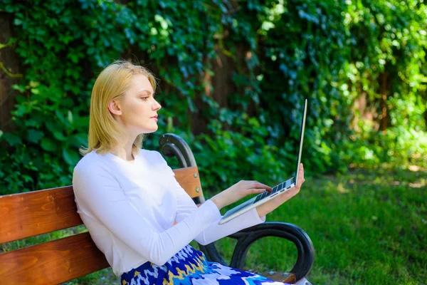 Szabadúszó előnyeit. Nő a laptop szerkezet háttér szabadtéri, zöld természet. Lady szabadúszóként dolgozik a parkban. Előnyeit és hátrányait egyre szabadúszó. Lány ül a padon, notebook — Stock Fotó