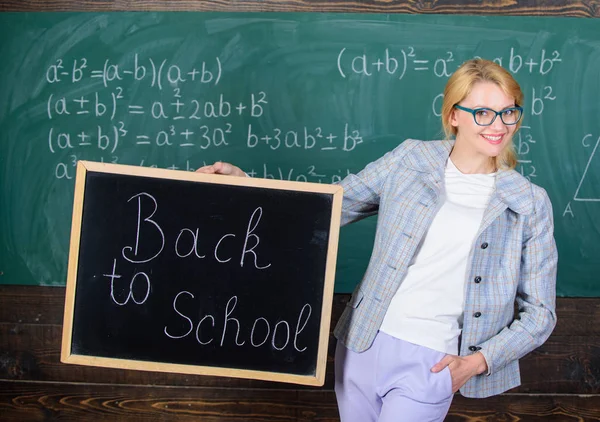 Début de la nouvelle saison scolaire. Le costume officiel d'enseignante tient l'inscription du tableau noir à l'école. Dame éducatrice en classe se préparer pour la nouvelle année scolaire. L'enseignant accueille la nouvelle année scolaire — Photo