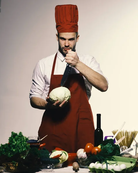 Mannen med skägg rymmer kål och kniv på grå bakgrund. Kock i Bourgogne enhetliga förbereder måltid. Matlagning koncept. — Stockfoto