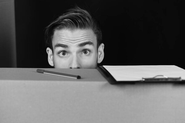 Man hiding behind cardboard boxes. Delivery and moving in concept: man hiding behind cardboard boxes