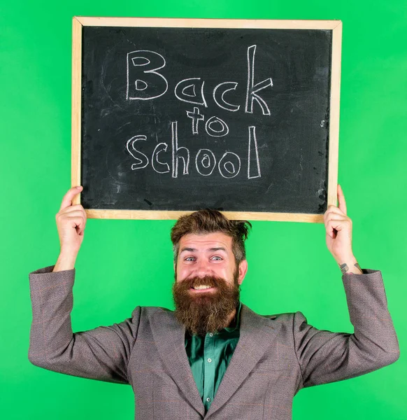 Назад до школи спеціальна пропозиція. Чоловік бородатий вчитель тримає дошку назад до шкільного напису на зеленому тлі. Спеціальна пропозиція зі знижкою та продажем шкільного сезону. Перевір це. Пропозиція для учнів — стокове фото