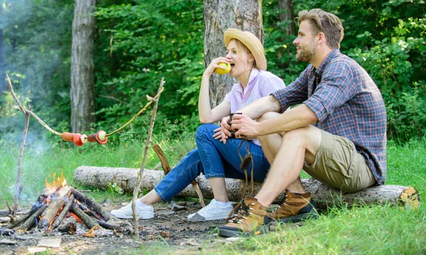 Couple romantic date near bonfire in forest. Couple relaxing sit on log having snacks. Pleasant picnic or romantic date nature background. Hike picnic date. Family enjoy romantic weekend in nature — Stock Photo, Image