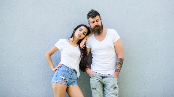 Pareja enamorada pasar el rato juntos fondo gris de la pared. Un par de jóvenes modernos con estilo. Un par de camisas blancas se inclinan entre sí. Hipster barbudo y elegante chica pasar el rato al aire libre. Pareja amorosa urbana — Foto de Stock