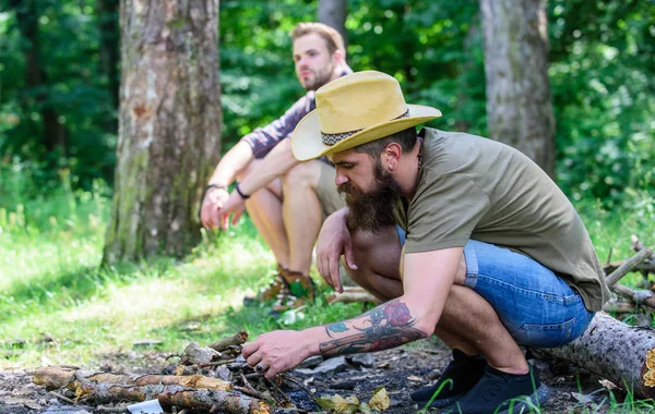 Homens de férias. Conceito de masculinidade. Guia final para fogueiras. Como fazer fogueira ao ar livre. Organizar os galhos da floresta ou paus de madeira. Homem brutal hipster barbudo prepara fogueira na floresta — Fotografia de Stock