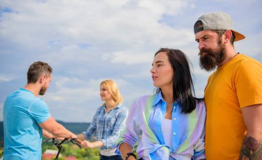 İyi vakit geçiriyor Bisiklet ile çift süre başka bir çift sıkılmış. Çiftler eğlence farklı şekilde gökyüzü arka plan harcamak. Bisiklet kiralayıp ve eğlenin. Bisiklet kiralama hizmeti kavramı. Kız için bisiklet almak