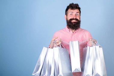 Satış ve indirim kavramı. Hippi bağımlısı yüz alışveriş veya Alışverişkoliğin gülümseyen üzerinde. Satış sezon indirimlerle alışveriş adam. Sakal ve bıyık taşımak alışveriş torbaları, açık mavi renkli olan adam