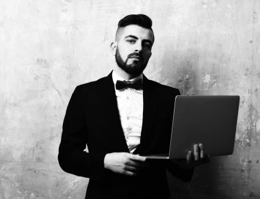 Şık görünümlü sakallı işadamı emin yüz ifadesi ile laptop tutar