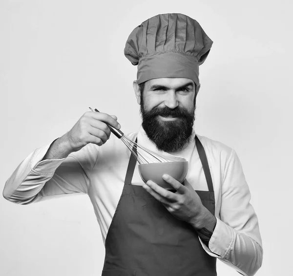 Homme avec barbe tient ustensiles de cuisine sur fond blanc. — Photo