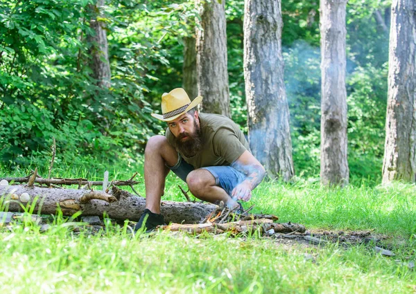 Como fazer fogueira ao ar livre. Organizar os galhos de madeira ou madeira varas de pé como uma pirâmide e coloque as folhas sob. Homem palha chapéu prepara fogueira na floresta. Guia final para fogueiras — Fotografia de Stock