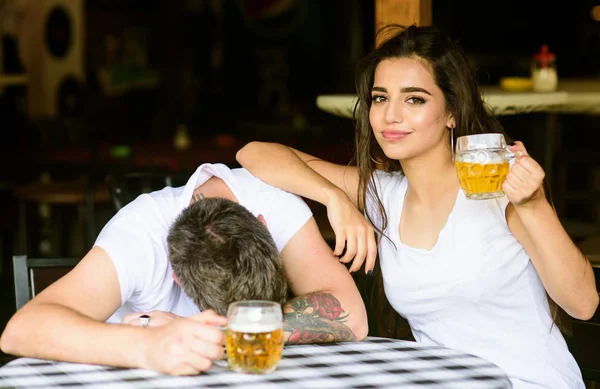 Enough for him. Best friends or lover drink beer in pub. Couple in love on date drinks beer. Man drunk fall asleep on table and girl with full beer glass. She knows tricks how to drink and stay sober