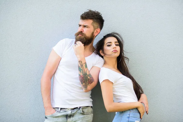 Youth stylish outfit. Couple white shirts cuddle each other. Couple friends hang out together grey wall background. Feel their style. Hipster bearded and stylish girl hang out urban romantic date