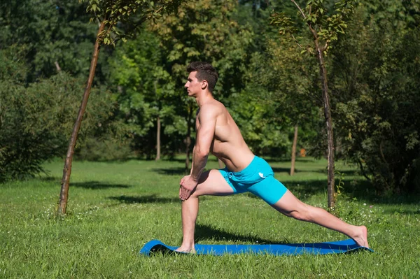 Fitness. treinamento homem muscular no tapete de fitness ao ar livre. atividade de verão fitness. homem fitness na grama verde. alongamento . — Fotografia de Stock