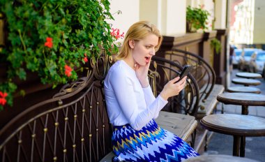 Şok edici içerik. Kadın yüz sörf Internet smartphone kafe Teras kentsel arka plan şaşırttı. Bayan sörf Internet beyaz kafede zaman harcamak. Kız arkadaş Smartphone kullanarak iletişim kurma