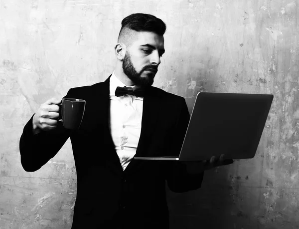 Forretningsarbeider med travelt tenkende ansikt holder en kopp og en bærbar PC – stockfoto