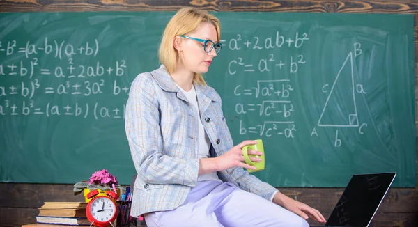 Take a minute break. Working conditions which prospective teachers must consider. Woman calm teacher holds mug drink sit table classroom chalkboard background. Working conditions for teachers