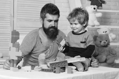 Arka planda oyuncakları olan baba ve çocuk blokları inşa ediyor.