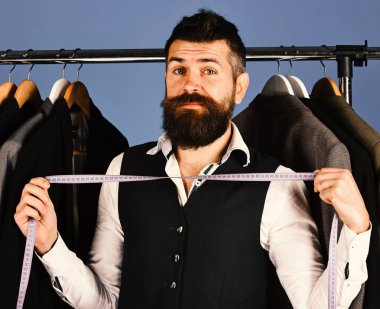 Mavi arka plandaki ceketlerin yanında meraklı yüzlü bir iş adamı..